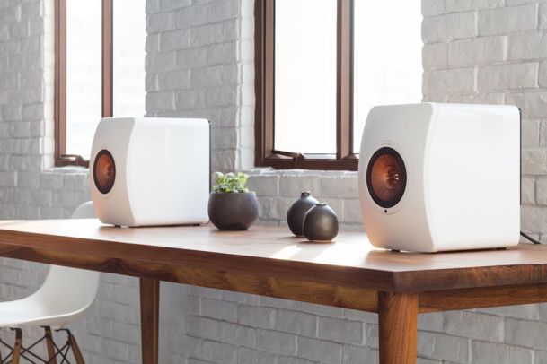 White Kef speakers on wooden table
