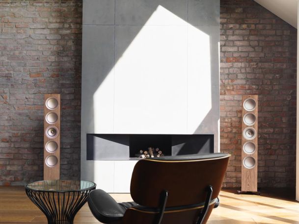 Wooden Kef speakers in front of brick wall